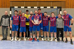 Florian Geier steht nach dem Spiel mit seinen Mannschaftskameraden vor einem Tor und hält ein Präsent in den Händen.